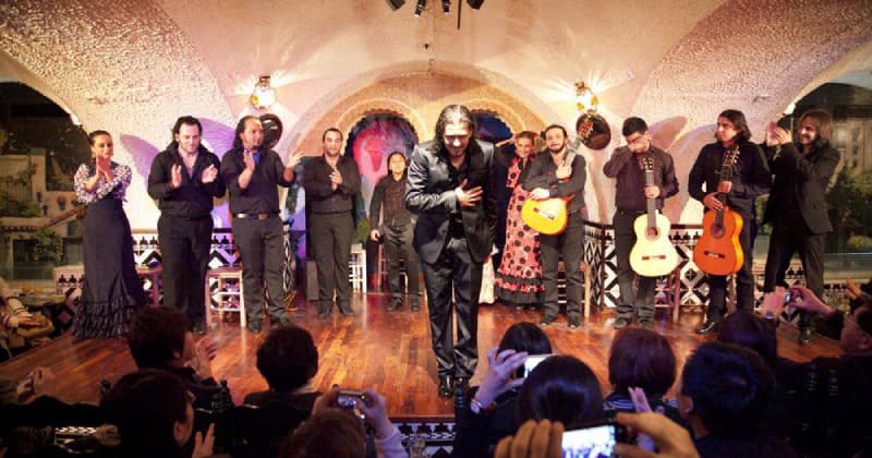 Fotografia del palco del locale Tablao Cordobes a Barcellona. Sul palco c'è un ballerino di Flamenco e dietro di lui diversi musicisti. In basso c'è il pubblico