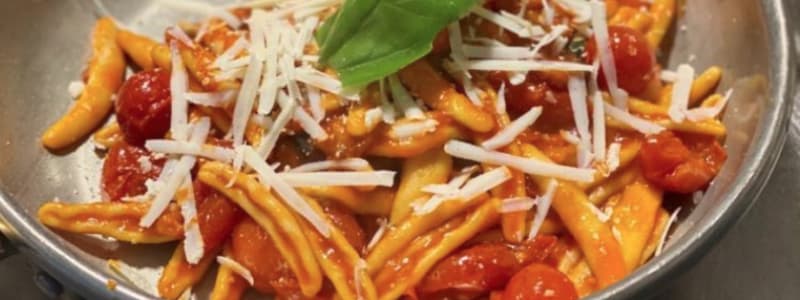 Fotografia ravvicinata della pasta con scaglie di parmigiano pomodoro e basilico in una padella