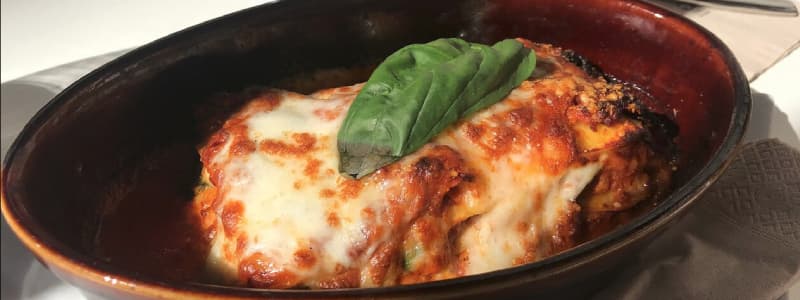 Fotografia ravvicinata di un piatto con pomodoro mozzarella e foglia di basilico su un tavolo