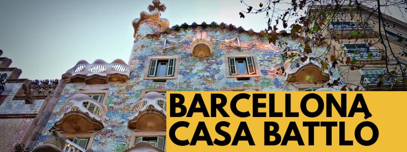 Fotografia dell'esterno di Casa Battlo a Barcellona con il muro decorato con motivo floreale e rettangolo arancione in basso a destra con scritta nera Barcellona Casa Battló