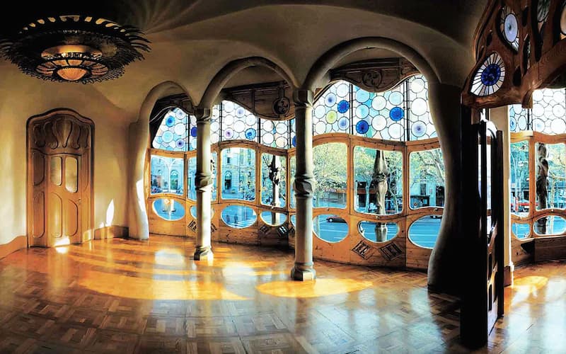 Fotografia dell'interno di Casa Battló a Barcellona con parquet, finestre di vetro e colonne