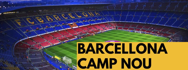 Fotografia dall'alto del campo di calcio Camp Nou di Barcellona con spalti rossi e blu con scritto in giallo Barcelona e rettangolo arancione in basso a destra con scritta nera Barcellona Camp Nou